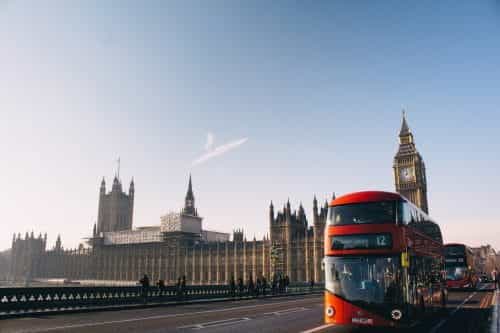 Roter Bus in London mit Buckingham Palace und Big Ben im Hintergrund.