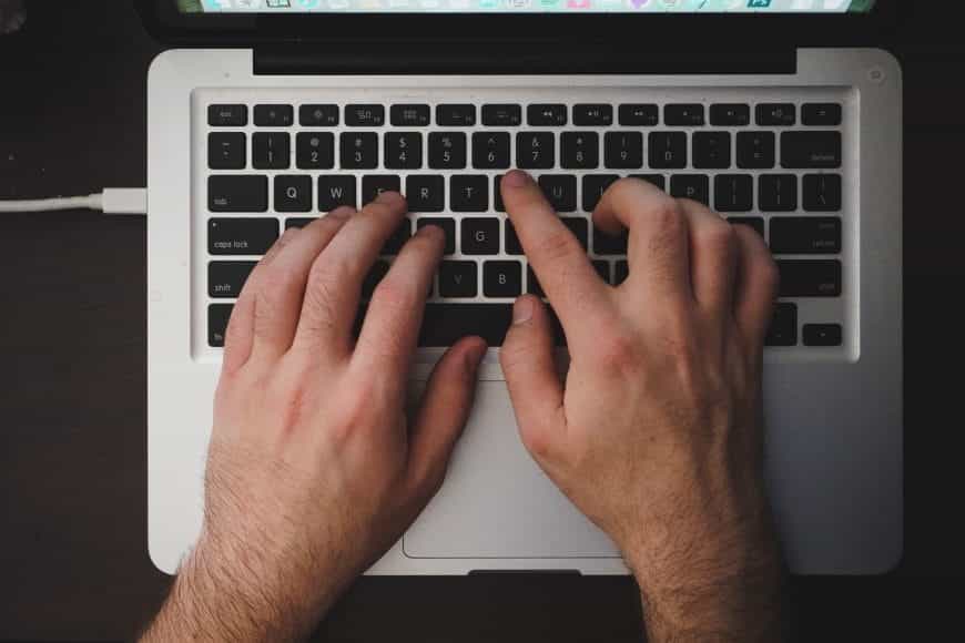 Mann tippt auf Laptop-Tastatur.