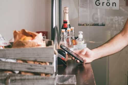 Mann bezahlt beim Bäcker mit dem Smartphone über Apple Pay.