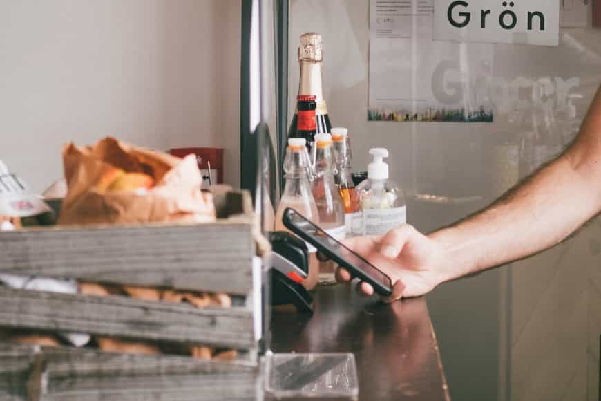 Mann bezahlt beim Bäcker mit dem Smartphone über Apple Pay.