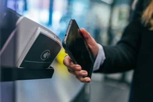 Geschäftsfrau bezahlt kontaktlos mit ihrem NFC-Smartphone.