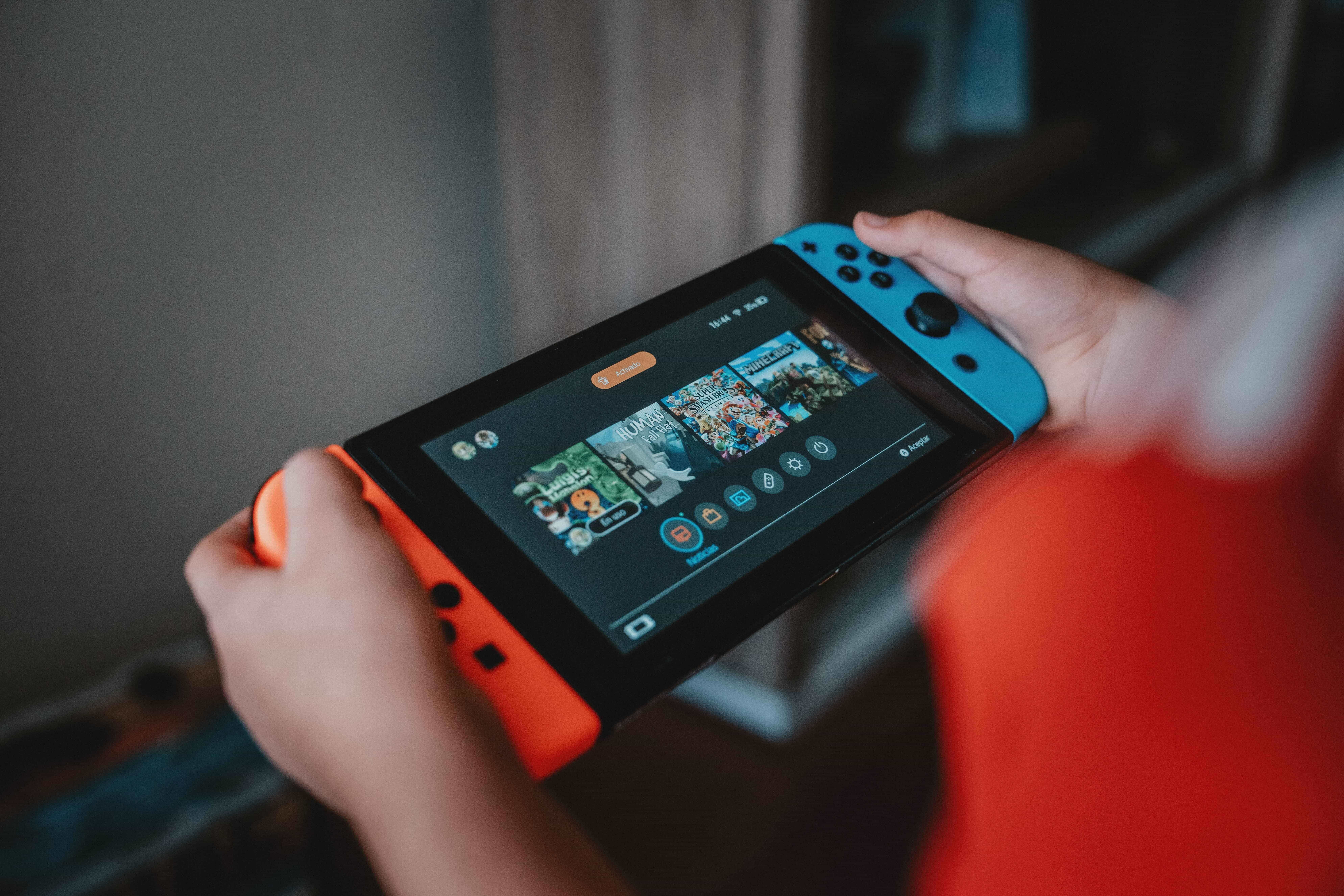 Seorang anak memegang konsol game seluler Nintendo Switch di tangannya dan memilih game.