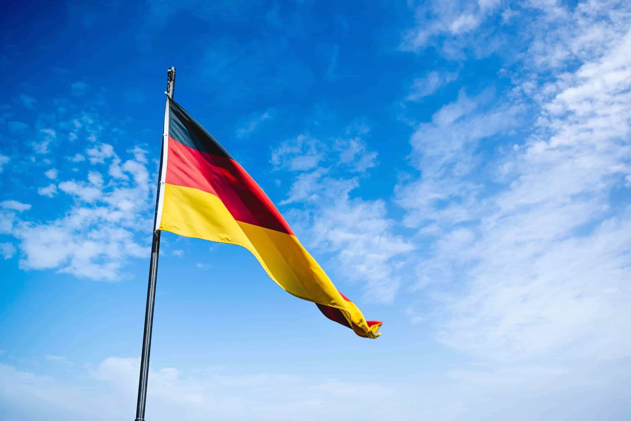 Die deutsche Nationalflagge weht an einem Mast an einem strahlend blauen Tag im Wind.