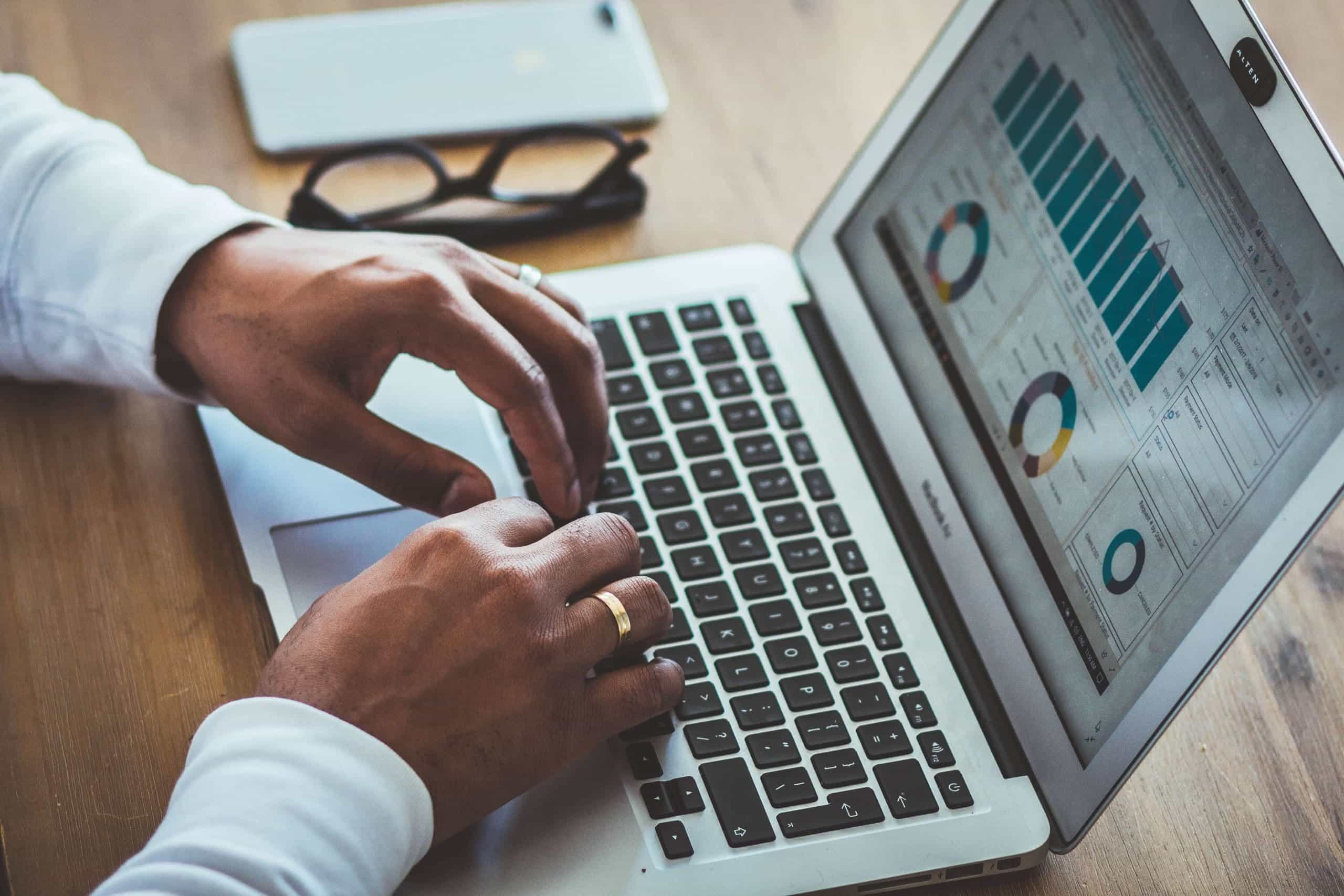 Männliche Hände tippen statistische Werte für eine Grafik in ein Notebook ein.