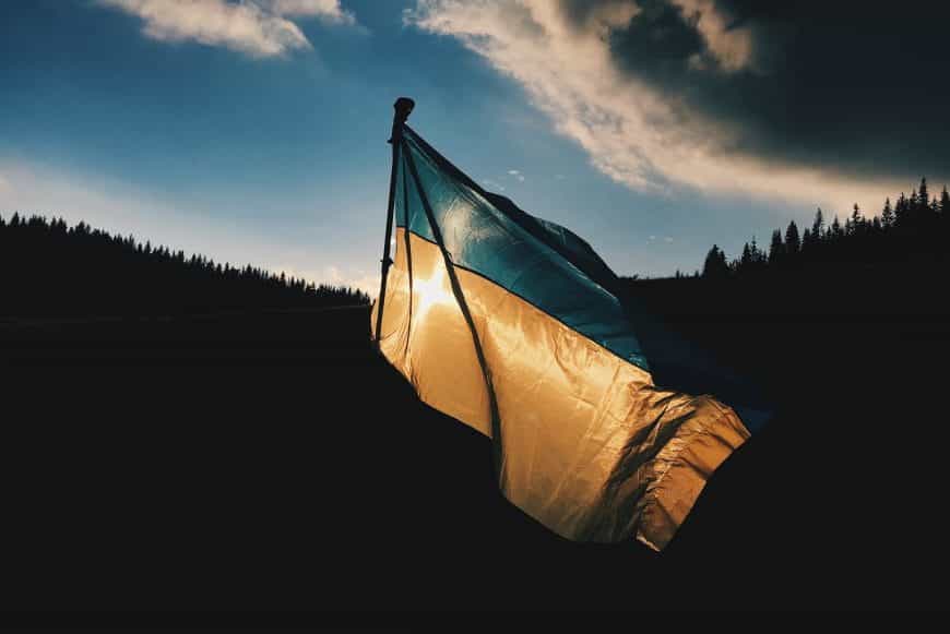 Bei Dämmerung ist eine wehende ukrainische Flagge im Wind zu erkennen.