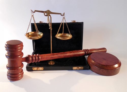 Eine Waage und ein Richterhammer als Symbole für Gerechtigkeit und Rechtsprechung.