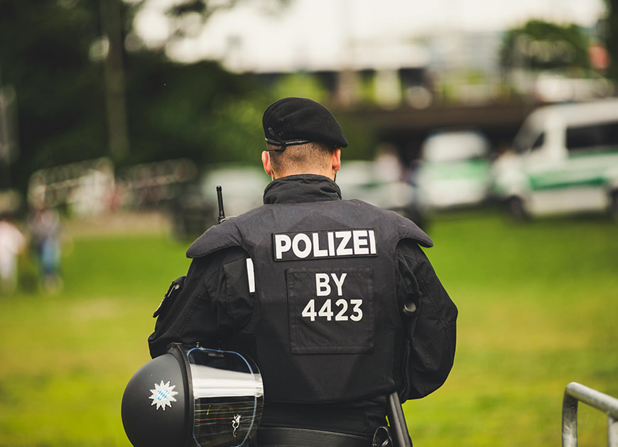 Ein Polizist in Einsatzkleidung hält seinen Helm und steht bereit für eine Razzia.
